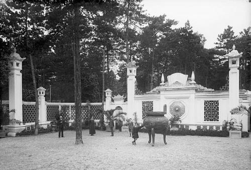 Figure 9 : Cour d'entrée du temple du souvenir indochinois : portique et urne funéraire. Jardin colonial de Nogent-sur-Marne. Photographie des années 1920. Cirad, [en ligne->https://catalogue.bnf.fr/ark:/12148/cb44789934v].